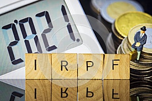 Income Tax Campaign 2021. Taxman sitting on coin stack. IRPF sign Macro photo
