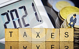 Income Tax Campaign 2021. Taxman sitting on coin stack. TAXES sign Macro photo