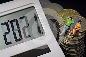 Income Tax Campaign 2021. Young Couple sitting on coin stack. Declaracion de la Renta macro photo