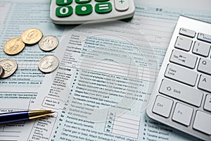 Income Tax Form 1040 with dollar coin, calculator od desk