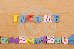 INCOME word on wooden background composed from colorful abc alphabet block wooden letters, copy space for ad text. Learning