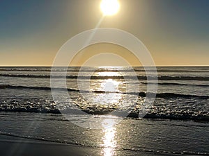 Incoming ocean waves and sunlight reflections from the sand beach at Agadir, Morocco, Africa at sunset