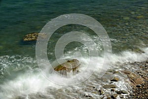 Incoming tidal waves washing over large kelp covered boulders on