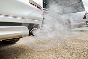 Incomplete combustion creates poisonous carbon monoxide from exhaust pipe of white car, air pollution concept