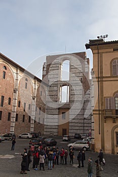 Incomplete facade of the planned Duomo nuovo and people on a square in front of it. Facciatone. Siena. Tuscany Italy.