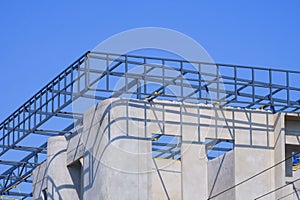 Incomplete precast bare concrete wall with roof beam outline on top of modern office building structure in construction site