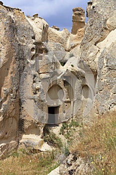 The inconspicuous entrance to the old ancient cave temple in the mountain valley of Cappadocia