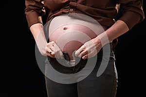 the inconvenience of pregnancy. a pregnant woman can't fasten her pants. gravity of movements of the pregnant woman