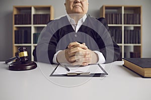 Incorruptible senior judge sitting at table with gavel and case papers in court of law