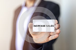 Increase sales inscription words on paper note in businessman hand