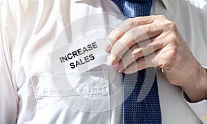 Increase sales inscription words on paper note in businessman hand