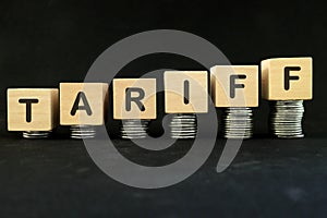 Increase tariff tax concept. Word in wooden blocks with increasing stack of coins.
