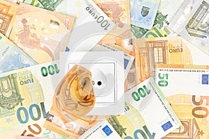 Increasing cost of electricity, expensive energy concept. White socket with euro banknotes background