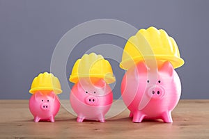 Increasing Pink Piggy Banks With Yellow Hard Hat