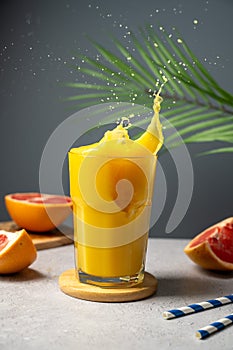 Increasing vitamins and minerals in diet. Glass of fresh orange juice with splashes and fresh fruits.