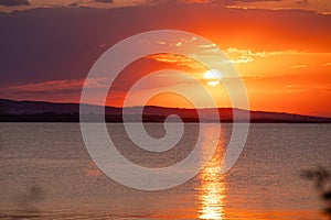 Incredible amazing, colorful summer sunsrise in Bulgaria Black coast. Orange sunset sky and reflection in the blue water