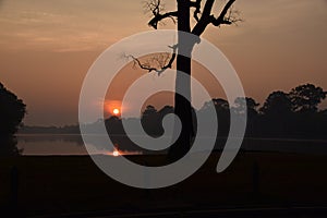 Sunrise over beautiful lake in angkor wat with sun reflecting in the water