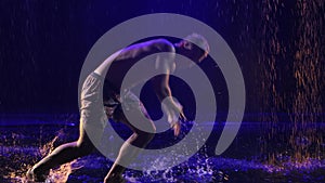 Incredible capoeira martial arts fighting in the rain in slow motion. Young male practicing martial art in a dark studio