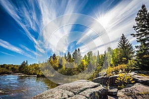 Incredible cirrus clouds  and huge flat stones in Old Pinawa Dam Park. Indian summer in Manitoba, Canada. The concept of photo