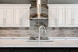 Incredible contemporary kitchen with white cabinets and glass backsplash.