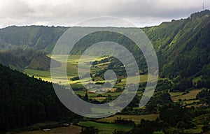 Incredible peaceful view of valley with green fields, forests and small villages. Background of cloudy sky