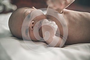 Incredible portrait of little baby boy which makes itself selfie laying on the bed