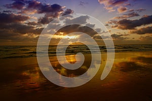 Incredible sunset with clouds reflected in wet sand on beach