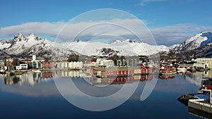 Incredible travel. Aerial view from flying drone of sea shore, snowy mountains, rorbuer in winter at sunset. Lofoten