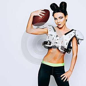 Incredibly beautiful, athletic brunette girl in a shoulderpads with American football demonstrating stunning amazing abs