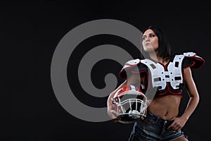 Incredibly beautiful, athletic brunette girl in a shoulderpads and an American football helmet demonstrating stunning amazing abs.