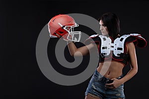 Incredibly beautiful, athletic brunette girl in a shoulderpads and an American football helmet demonstrating stunning amazing abs.