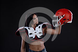 Incredibly beautiful, athletic brunette girl in a shoulderpads and an American football helmet demonstrating stunning amazing abs.