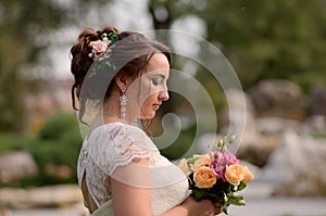 Incredibly beautiful bride with bouquet of roses. Romantic accessory of fiancee. Long haired girl in wedding gown