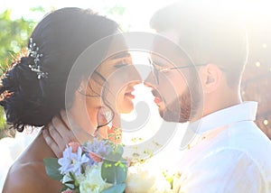 An incredibly beautiful brunette and a bearded guy in glasses kiss at sunset on their wedding day