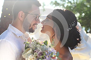 An incredibly beautiful brunette and a bearded guy in glasses kiss at sunset on their wedding day