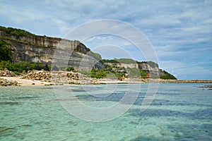 An incredibly beautiful deserted tropical beach under a cliff with clear, clean ocean water on the popular tourist island of Bali
