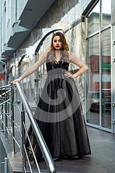 incredibly beautiful full-length woman posing among the city in an amazing black evening dress.