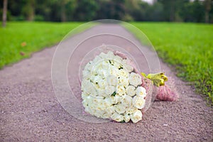Incredibly beautiful large bouquet of white roses on a sandy path in the garden