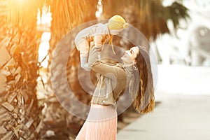 Incredibly beautiful mother holding in her arms her daughter and kissing outside. Fashionable stylish look