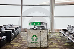 Ind Recycles recycling receptacle in empty airport terminal with chairs and gray windows