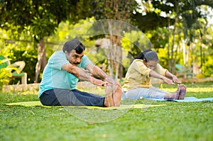 Indain senior couple at morning doing yoga at park - concept of healthy active lifestyle, outdoor fitness and wellness