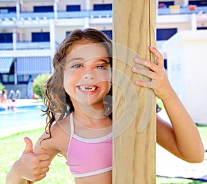 Indented kid girl ok gesture in pool garden