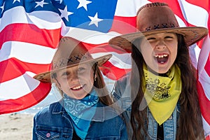 Independence Day. Patriotic holiday. Happy kids, cute two girls with American flag. Cowboy. USA celebrate 4th of July