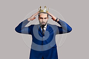 Independent bearded man wearing golden crown, looking with arrogance, confidence, privileged status.