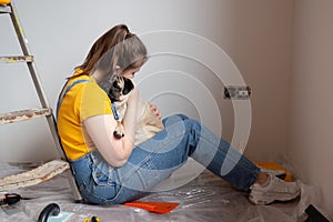 Independent single female sitting on floor and rest with pet dog in her new house during renovation, construction tools