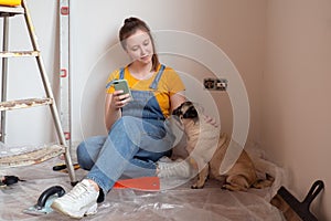 Independent single female sitting on floor and rest with pet dog in her new house during renovation, construction tools