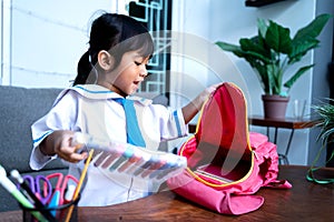 Independent young kindergarten student preparing her own stuff before going to school