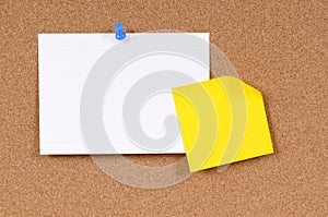 Office index card with post it style yellow sticky note pinned to cork board, copy space