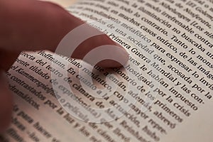 Index finger of the left hand pointing to the text line of a book