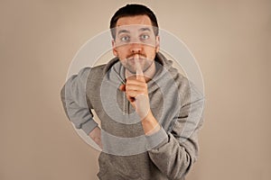 With an index finger pressed to his lips, the man requests silence in a calm manner. His composed expression enhances